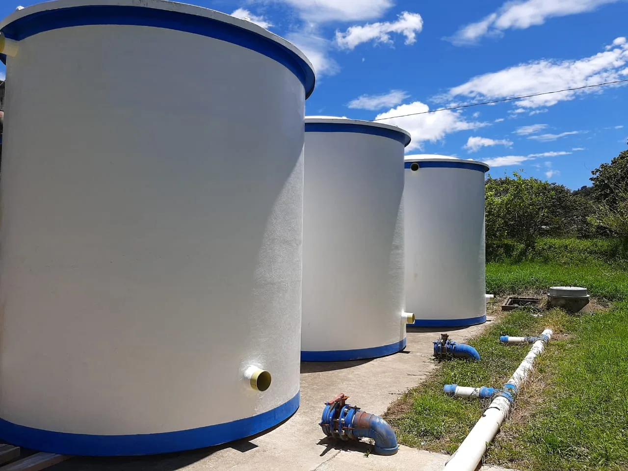 Batería de tres tanques verticales en fibra de vidrio con la tubería ya conectada en un acueducto.