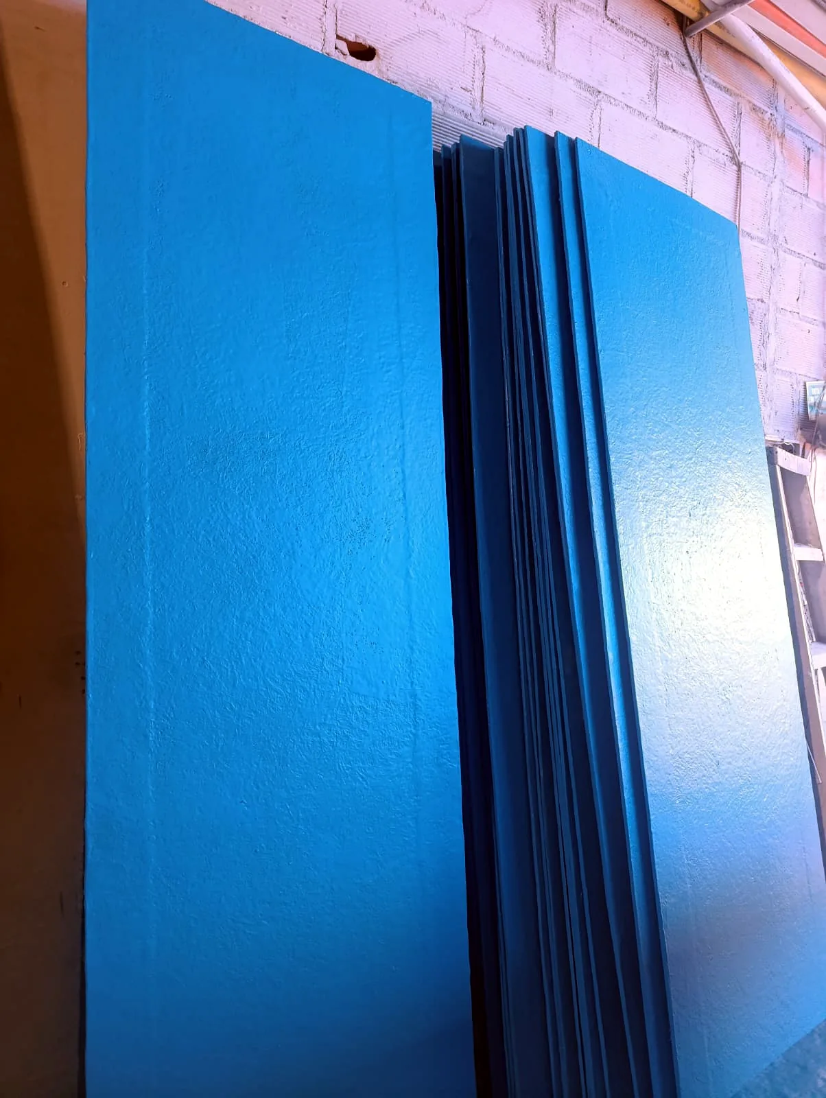 Lote de placas en PRFV apiladas contra el muro de la planta, listas para despachar.
